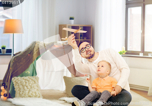 Image of father and son playing with toy airplane at home
