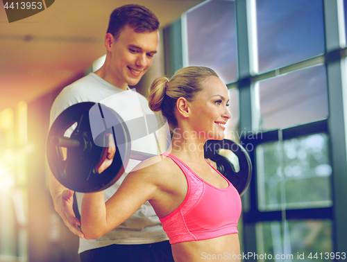 Image of smiling man and woman with barbell in gym