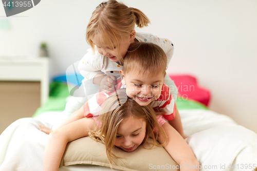 Image of happy little kids having fun in bed at home