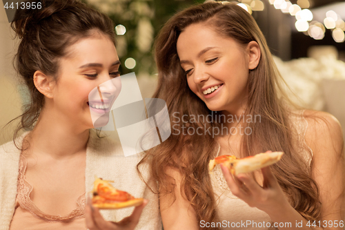 Image of happy female friends eating pizza at home