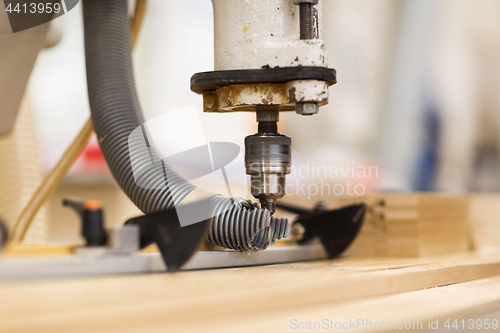 Image of drill press machine and wooden board at workshop