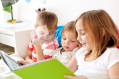 Image of little kids reading book in bed at home