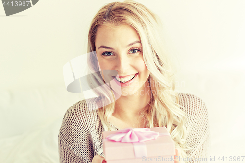 Image of happy young woman with gift box at home