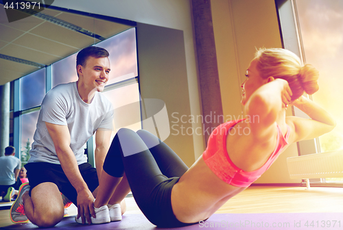 Image of woman with personal trainer doing sit ups in gym