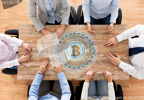 Image of business team at table with bitcoin icon