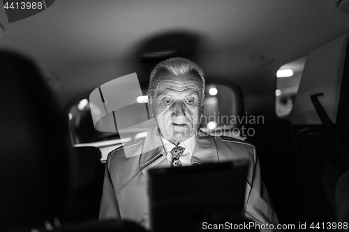 Image of Businessman with a digital tablet sitting in the back seat of a car