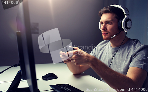 Image of man in headset playing computer video game at home