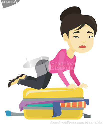 Image of Young woman trying to close suitcase.