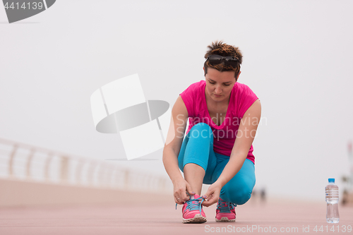 Image of Young woman tying shoelaces on sneakers