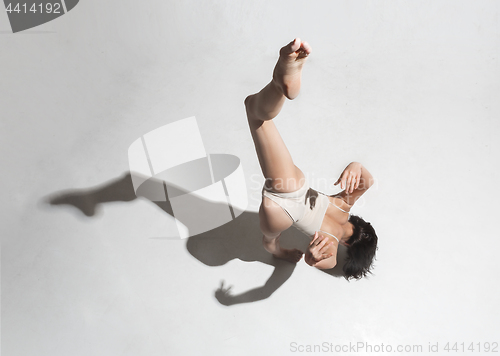 Image of Young beautiful dancer in beige dress dancing on gray background