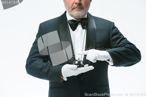 Image of Senior waiter holding bell