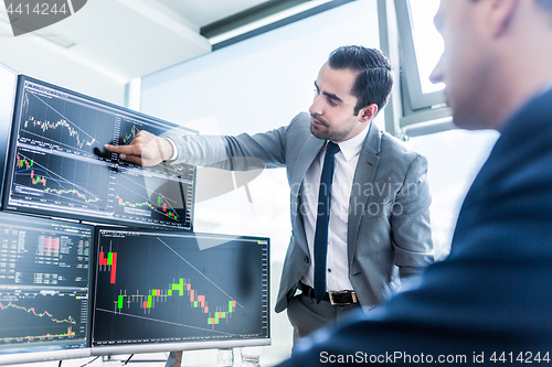 Image of Stock brokers looking at computer screens, trading online.