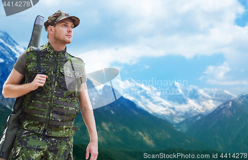 Image of young soldier or hunter with gun over mountains