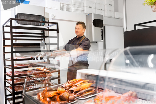 Image of seller with smoking tray at fish shop