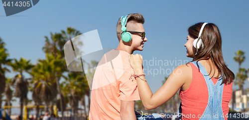 Image of teenage couple with headphones at venice beach