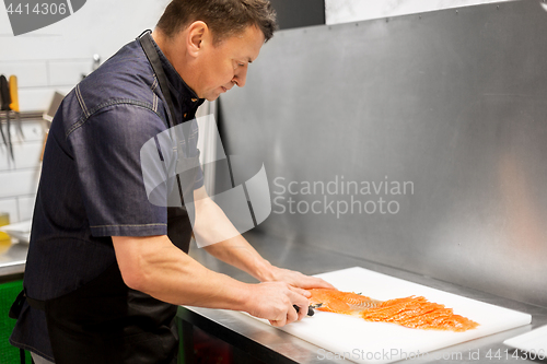 Image of man slicing smoked salmon fish fillet