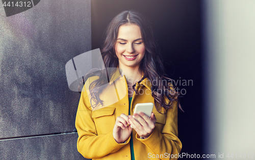 Image of smiling young woman or girl texting on smartphone