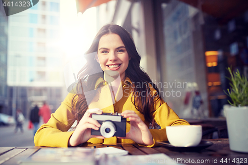 Image of happy tourist woman with camera at city cafe