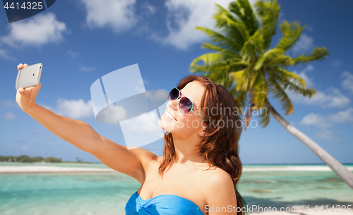 Image of woman taking selfie by smartphone on beach