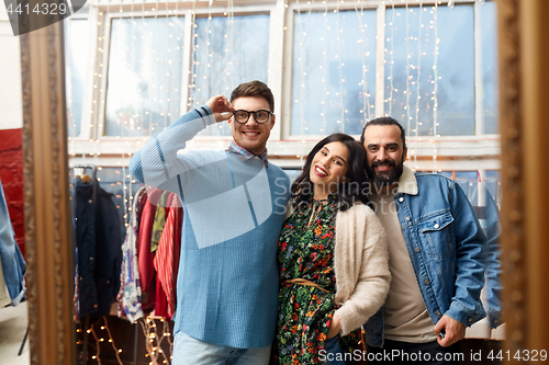 Image of happy friends at mirror at vintage clothing store