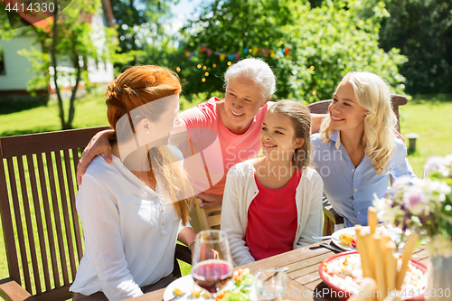 Image of happy family having dinner at summer garden