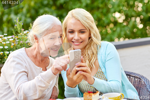 Image of daughter and senior mother with smartphone at cafe