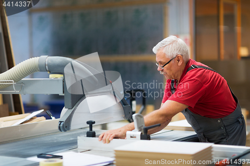 Image of carpenter working with panel saw at factory