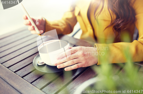 Image of close up of woman texting on smartphone at cafe