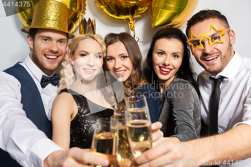 Image of happy friends clinking champagne glasses at party