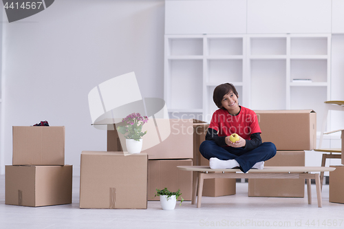 Image of boy sitting on the table with cardboard boxes around him