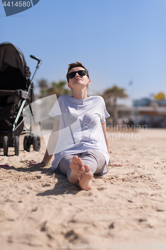 Image of Young mother with sunglasses relaxing on beach