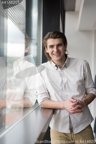 Image of young businessman in startup office by the window