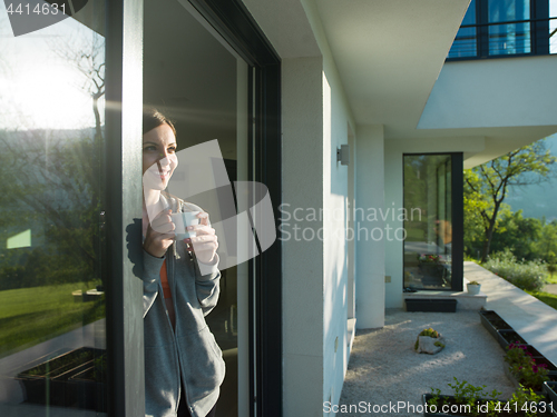 Image of woman drinking coffee in front of her luxury home villa