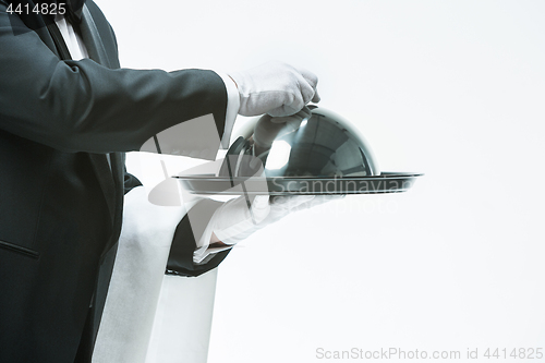 Image of Close up waiter hand with tray and metal cloche lid cover