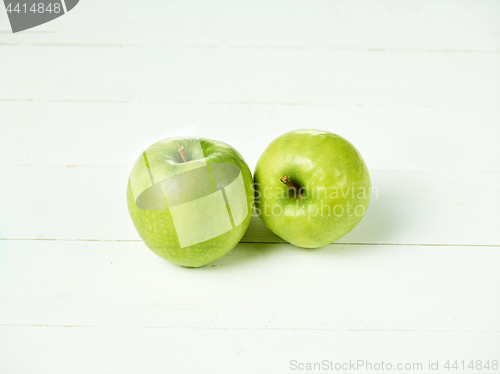 Image of Shot of two fresh green apples with green leaf on a table.