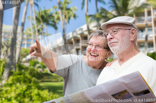 Image of Happy Senior Adult Couple Tourists with Brochure Next To Tropica