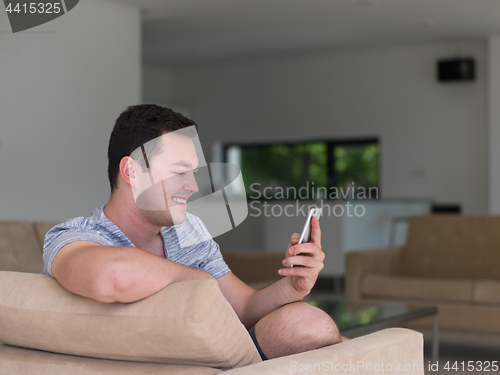 Image of young man using a mobile phone  at home