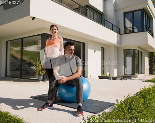 Image of woman and personal trainer doing exercise with pilates ball