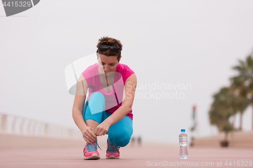 Image of Young woman tying shoelaces on sneakers