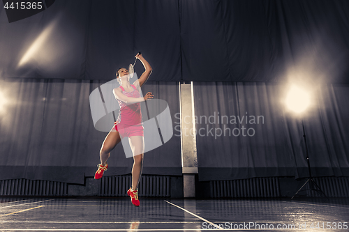 Image of Young woman playing badminton at gym