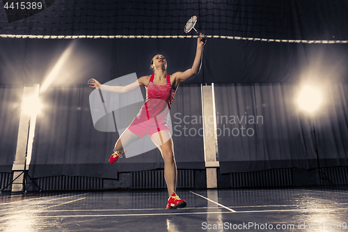 Image of Young woman playing badminton at gym