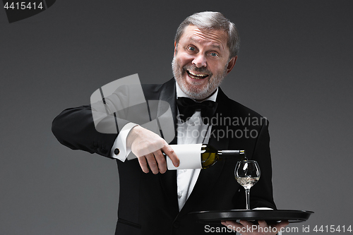 Image of professional waiter in uniform is serving wine