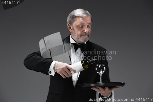 Image of professional waiter in uniform is serving wine
