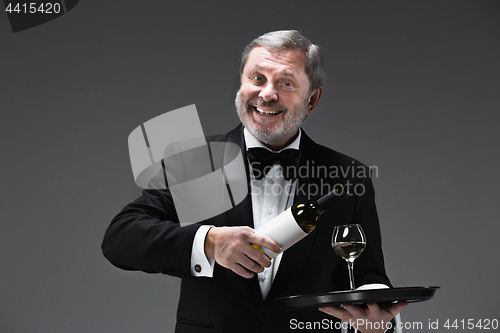 Image of professional waiter in uniform is serving wine