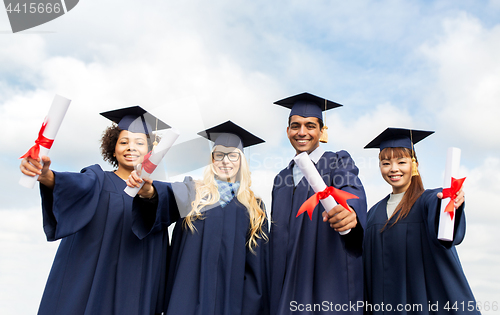 Image of happy students in mortar boards with diplomas