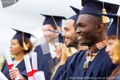 Image of happy students in mortar boards with diplomas