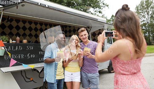 Image of woman photographing friends eating at food truck