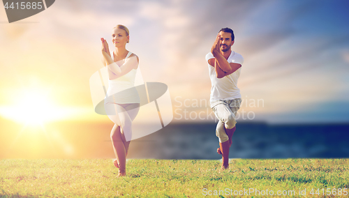 Image of couple making yoga eagle pose outdoors