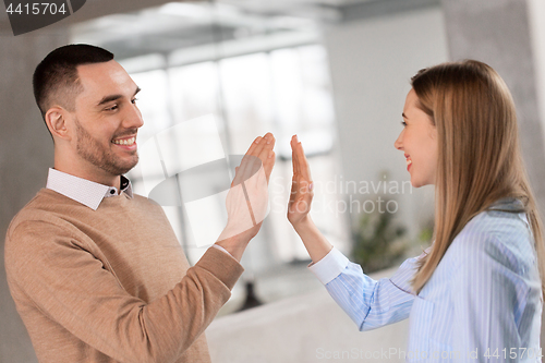 Image of man and woman making high five at office