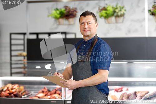 Image of seller at fish shop writing to clipboard